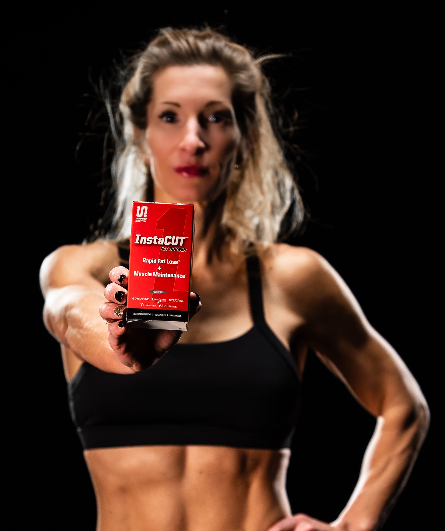 keri Shaw holding a red supplement box labeled 'InstaCUT' against a black background