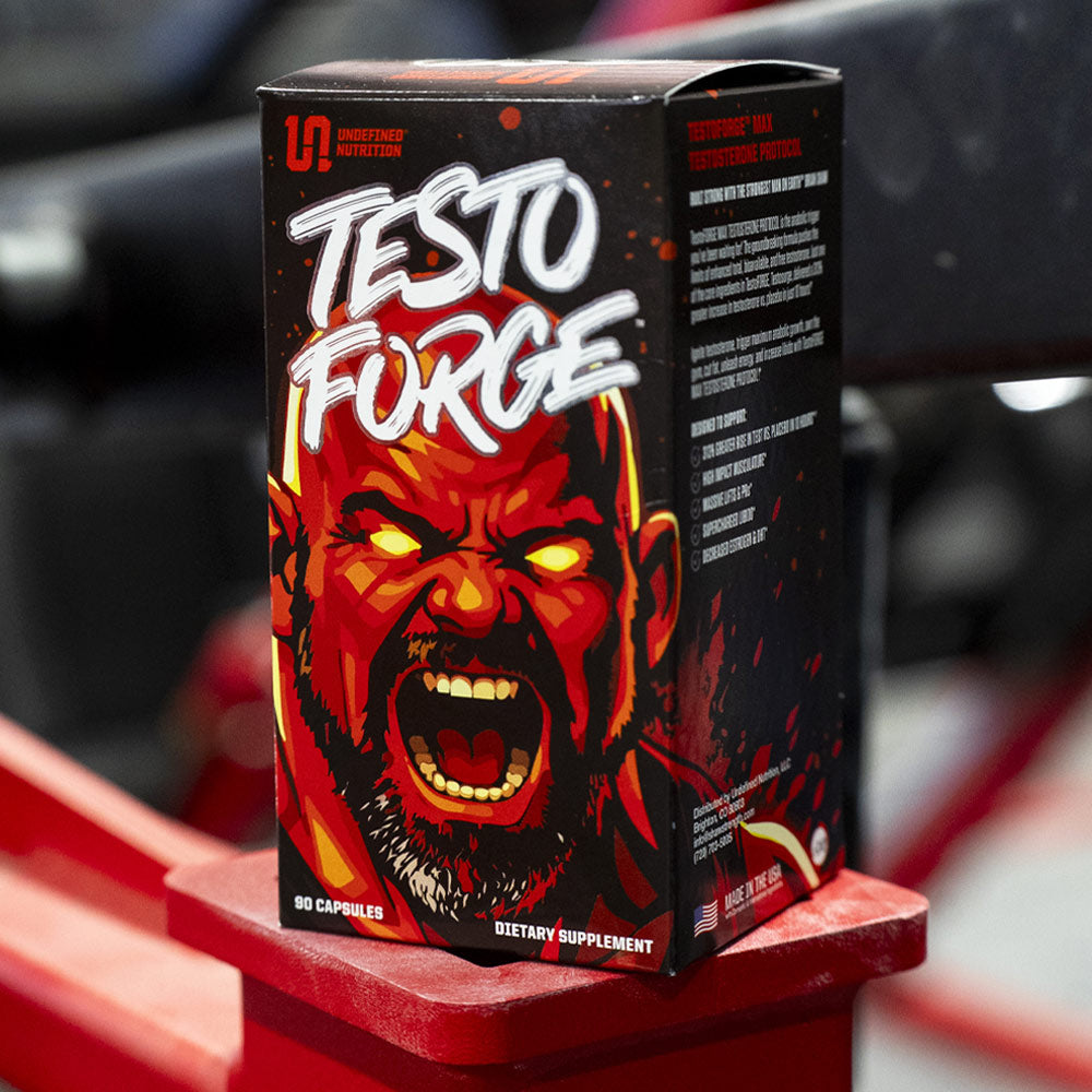 A box of TestoFORGE dietary supplement, featuring an illustration of Brian Shaw on a black background, displayed on a red stand.