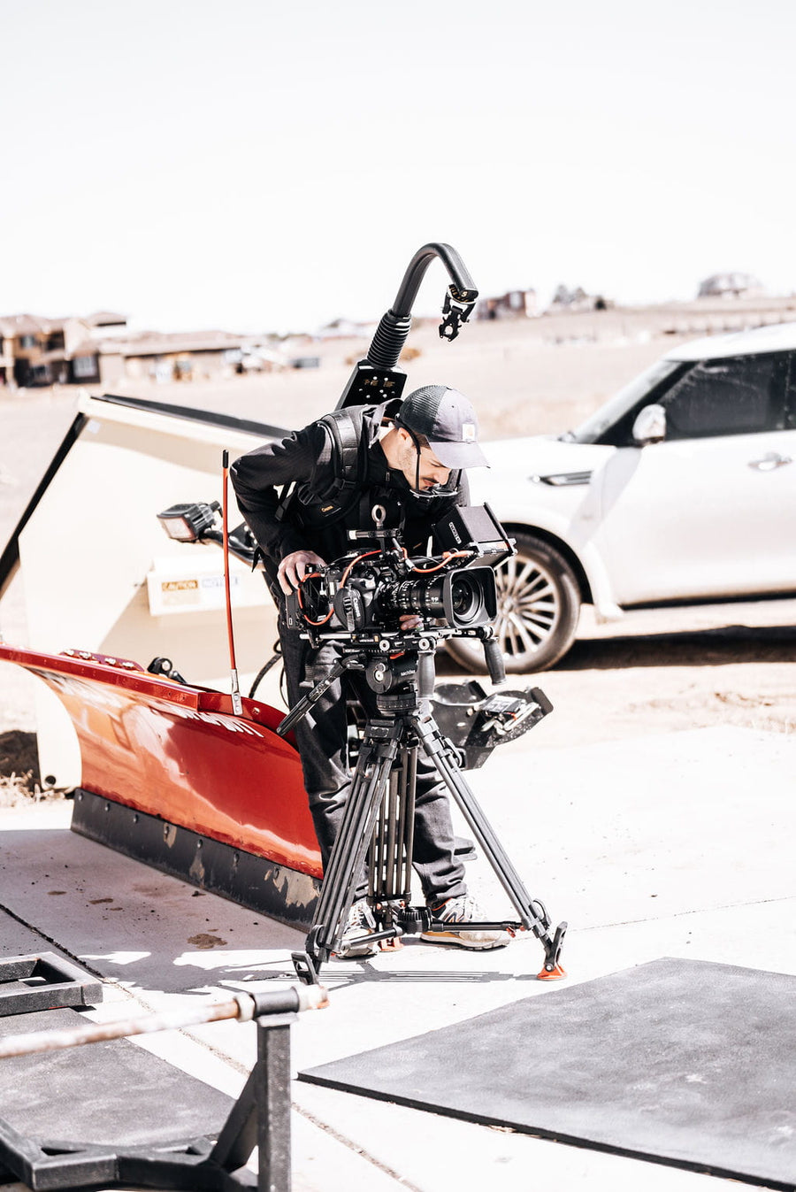 Camera operator framing a shot on a tripod outdoors